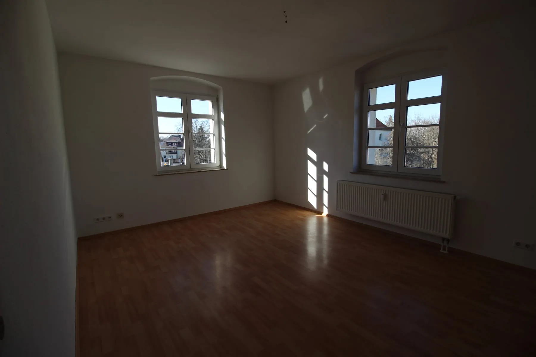 Wohnzimmer mit zwei Fenstern und Laminatboden
