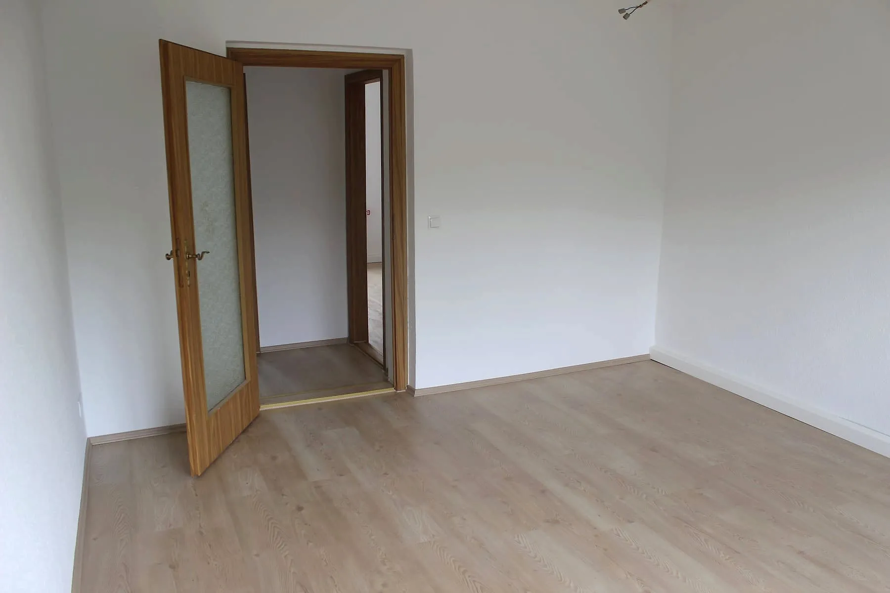 Wohnzimmer mit Flügeltür und Laminatboden