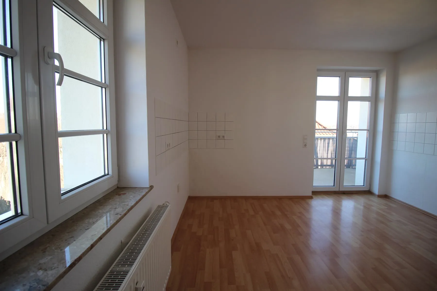 Küche mit Fliesenspiegel und Zugang zum Balkon